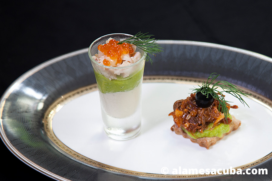 Chupito con Smetana, guacamole, escabeche y caviar, acompañado de una galletita de masa quebrada con guacamole, ropa vieja y aceituna negra.