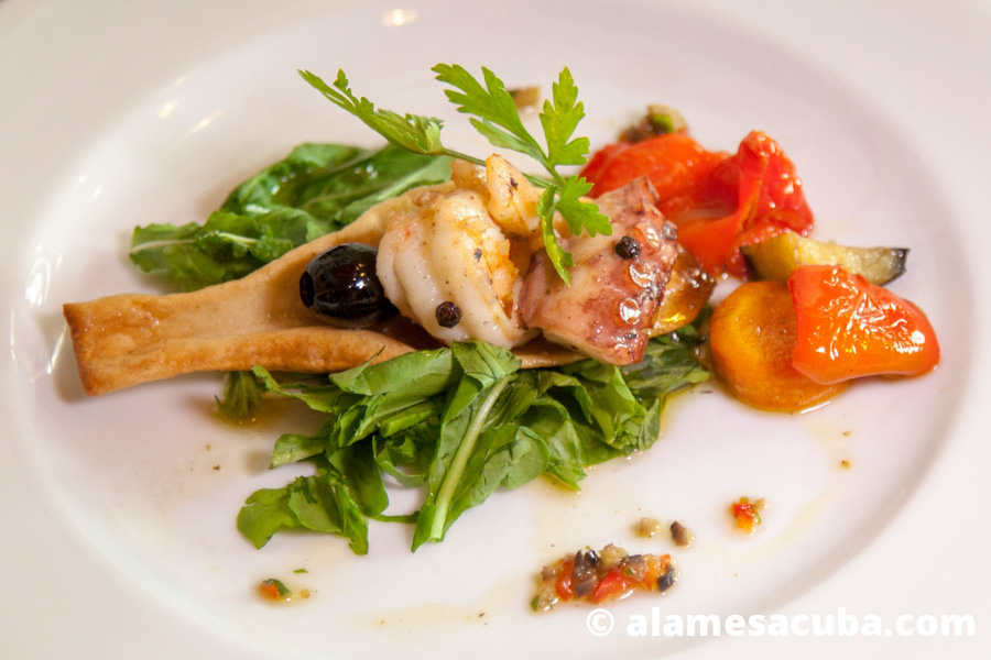 Escabechado de mariscos con vegetales montados en una focaccia a las finas hierbas.