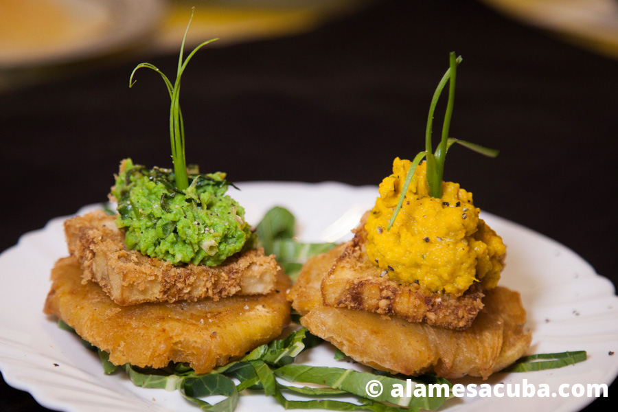 Dos tostones con berenjena empanada, uno acompañado de crema de calabaza y zanahorias y otro con crema de chícharo verde.